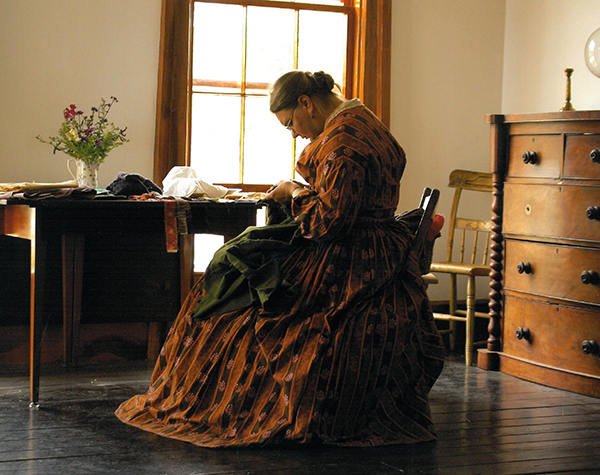 Women sewing inside historic historic setting at Old World Wisconsin